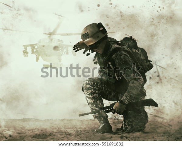 US soldier in the desert during the military\
operation turning to combat helicopter approaching covering his\
eyes. Backup is coming