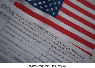 U.S. Standard Certificate Of Live Birth Application Form Next To Flags Of USA. Birthright Citizenship Concept. Diagonal View.  