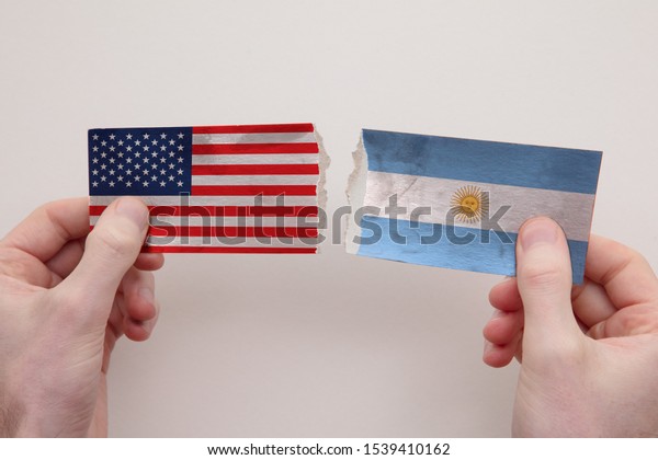 USA and Argentina paper flags ripped apart.\
political relationship\
concept