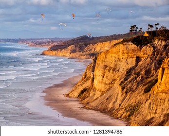 USA, California, La Jolla. Paragliders float over Black's Beach in late afternoon