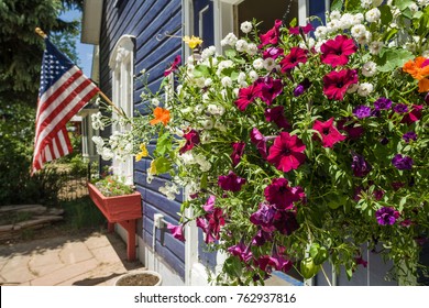 USA, CO, CRESTED BUTTE -CIRCA JUN 2008 - Flowers in hanging baskets and American flag at a house