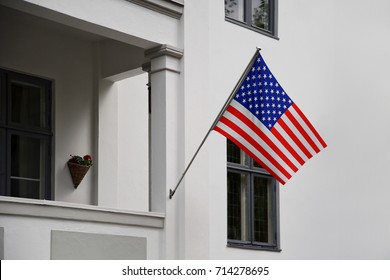 USA flag. American flag displaying on a pole in front of the house. National flag of United States of America waving on a home hanging from a pole on a front door of a building.