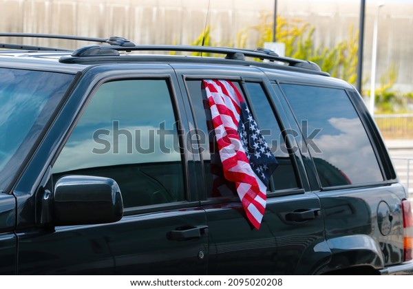 USA flag\
hangs from the car window, selective\
focus