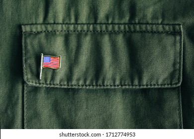 USA Flag Pin Badge On Green Jacket Pocket. Top View. Copy, Empty Space For Text