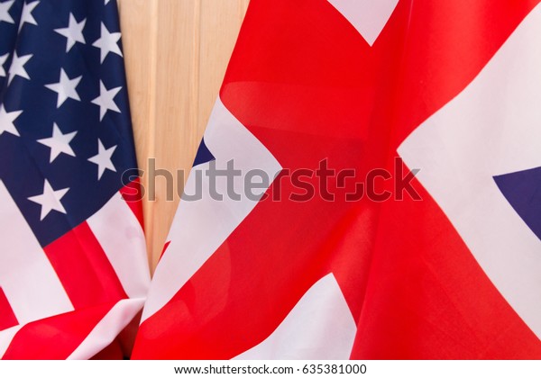 USA flag and\
UK Flag on wooden background\
light.