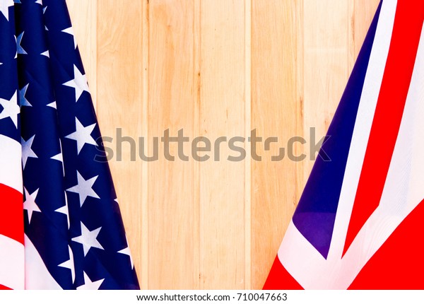 USA flag and\
UK Flag on wooden background\
light.
