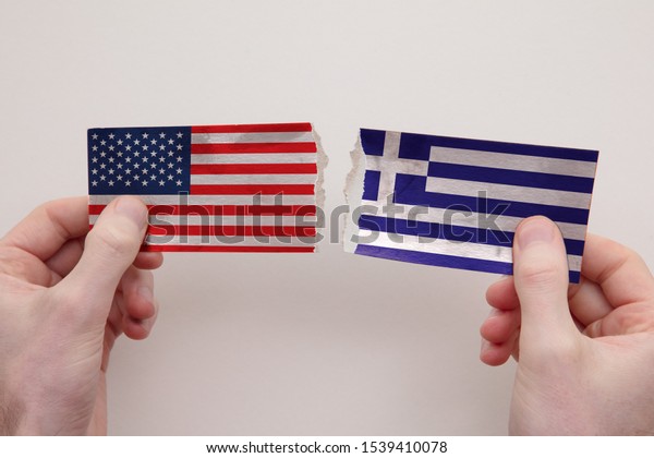 USA and Greece paper flags ripped apart.\
political relationship\
concept
