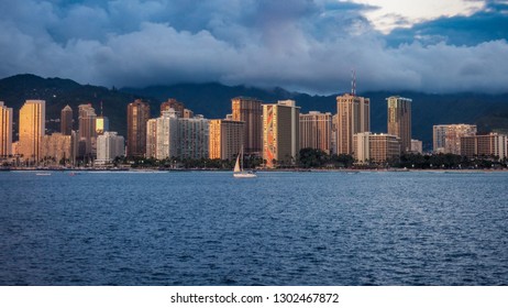 USA, HAWAII - AUGUST 31, 2018: Yacht sailing with Waikiki skyline in background at dusk