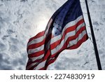 USA national flag waving on wind against blue sky. American stars and stripes spangled banner as symbol of democracy