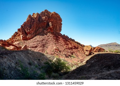 USA, Nevada, Clark County, Gold Butte National Monument. A Sandstyone Rock Wall Towers Over Gray Gypsum Hills Darkened By Shade.