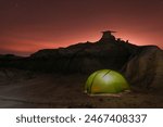 USA, New Mexico, Bisti Badlands - a green tent illuminated from within against eroded rocks at night in the Bisti Badlands after sunset