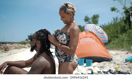 USA, Smiling woman doing mans hair on beach - Powered by Shutterstock