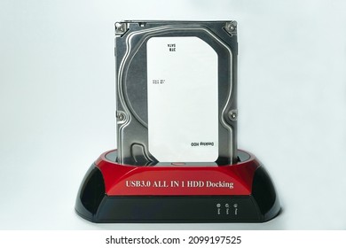 USB 3.0 HDD docking station is an adapter for reading 2.5 inch or 3.5 inch hard drives via USB cable. Red and black HDD docking made of plastic on white background isolated, 3 TB HDD installed.