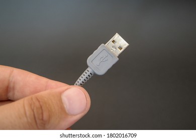 USB cable in hand on dark background