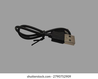 USB cable isolated on a gray background. A USB (Universal Serial Bus) cable is a standard cable and connector used to connect electronic devices to a computer, laptop, or power adapter. Its primary function is to transfer data and supply power (charging batteries) between devices