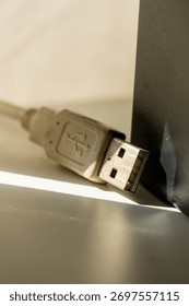 A USB cable laying on a table. The cable is white and has a USB logo impress on it
