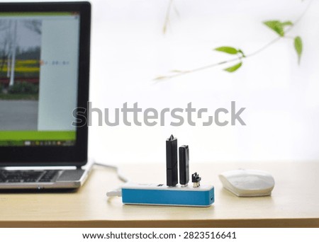 USB card reader hub with memory cards and flash drives on a desk beside a laptop and mouse in a clean workspace.