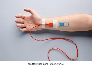 USB charge cable plugged in to a male arm with battery charging symbol. Tiredness, recharging, vitality, endurance, overwork, stamina, fatigue or life energy concept.