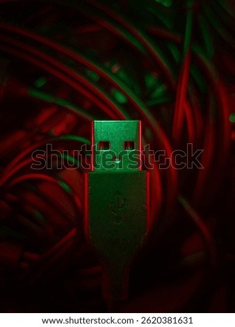 USB connector surrounded by a tangle of cables, illuminated with dramatic red and green lighting.