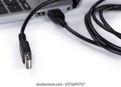 USB extension cable, equipped with plug and receptacle of Standard-A on the edges, connected to the laptop on a white background, view close-up in selective focus