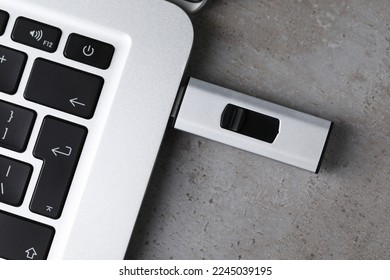 Unidad de flash Usb conectada al portátil en mesa gris claro, vista superior