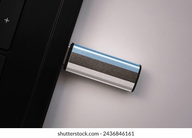 usb flash drive in notebook computer with the national flag of estonia on gray background. concept