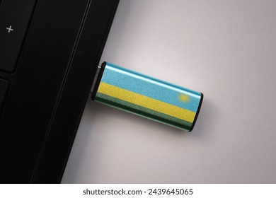 usb flash drive in notebook computer with the national flag of rwanda on gray background. concept