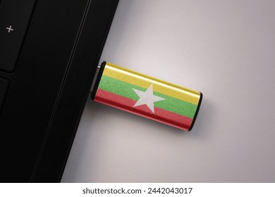 usb flash drive in notebook computer with the national flag of myanmar on gray background. concept