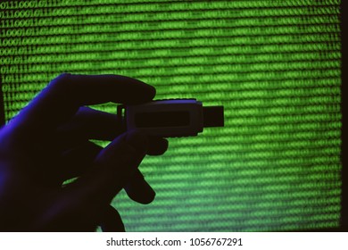 USB flash drive on a background of green binary code. A man holds a USB flash drive on the background of a computer monitor. vintage photo processing