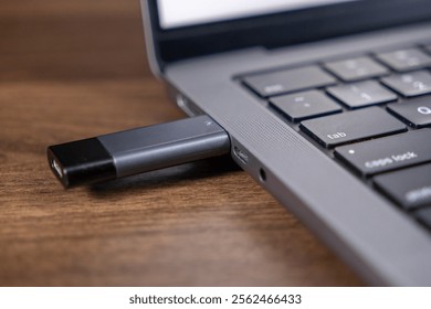 usb flash drive plugged into laptop usb-c port for data transfer on wooden desk