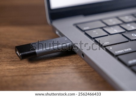 usb flash drive plugged into laptop usb-c port for data transfer on wooden desk