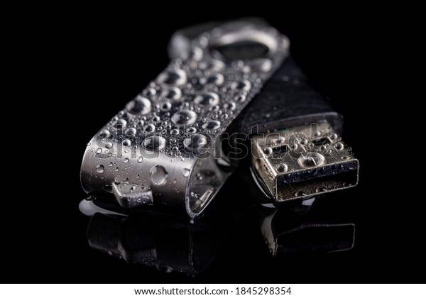 USB flash\
drive with water drops on the table. Electronic data storage device\
poured over with water. Dark\
background.