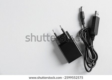 USB power adapter and charge cable on white background, flat lay. Space for text