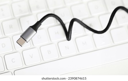 Usb type c cable against laptop keyboard background. Fast charge concept. Smartphone accessories closeup
