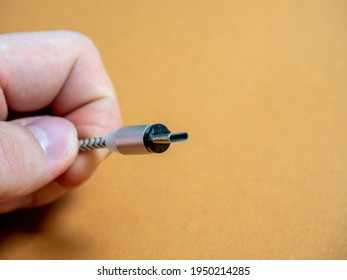 The usb type C cable is collapsible with a magnetic attachment in your hand on a brown background. Copy space
