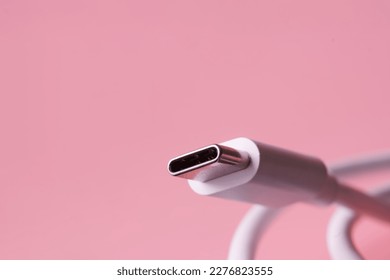 USB Type-C connector with a white wire on a pink background. Selective focus. Macro. Close-up