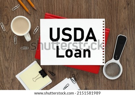 USDA loan notepad on the background of a wooden table. text on white paper of a red notepad near a magnifier.