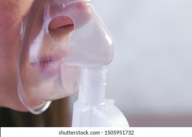 Use nebulizer and inhaler for the treatment. Young woman inhaling through inhaler mask