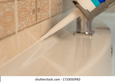 Use Of Silicone Or Sealant For Fixing A Sink In Bathroom Close Up