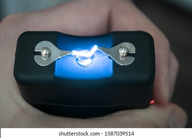 The Use Of A Stun Gun With A Powerful Electric Discharge. Personal Taser For Protection Against Bandits Is In The Hands. . Turning On The Device For Self-defense. View From Above