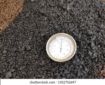 Use a thermometer to measure the temperature of hot mix asphalt.