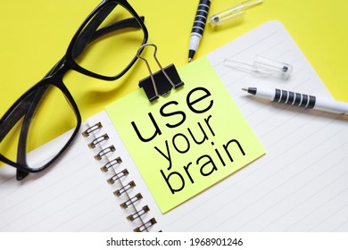 Use Your Brain. Text On Bright Yellow Sticker. On The Blanket. Yellow Background And Black Glasses Near The Sticker.