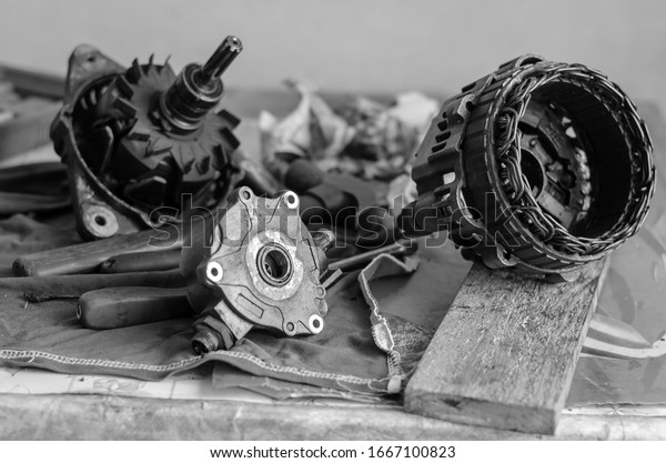 Used car generator on the\
table. Fully disassembled DC generator. Repair used generator. Auto\
repair shop or service center. Selective focus. Black and white\
photo