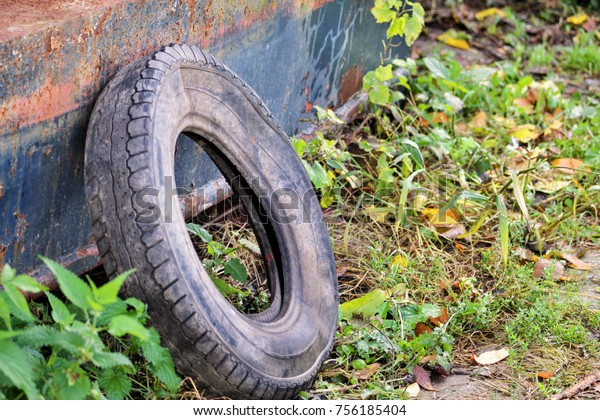 Used car tire left in nature. Old used car\
tyre left tossed by cost of water. The problem of trash on the\
beach river caused by man-made pollution and environmental in\
concept. Nature is\
destroyed.