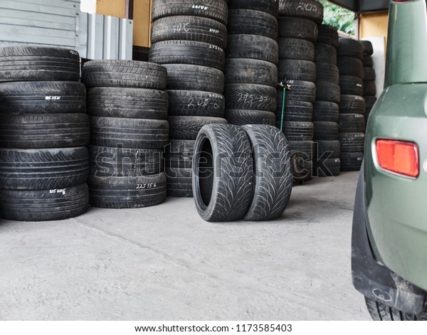 Used car\
tires stacked in piles at tire fitting service. Old wheels. Wheels\
for repair shop. Car service\
concept