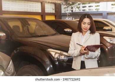 Used Car Trade Concept : Asian Businesswoman Or A Used Car Dealer Checks Vehicle Records And The Number Of Cars Parked In Garages With Pickup Trucks Popular With The Recession.