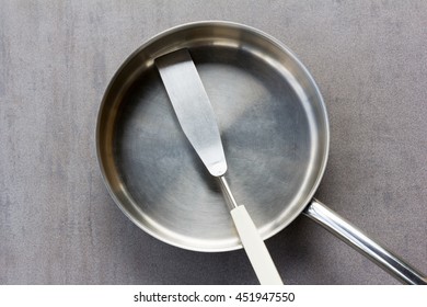 Used Clean Empty Stainless Steel Frying Pan And Spatula Overhead View On The Gray Background, Closeup Top View