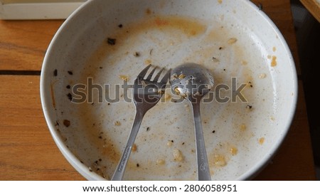 Used dinner plate with spoon and fork after a meal on a restaurant table. Concept of finished dining, everyday life, lunch break, casual eating, customer presence, and human activity without people. Authentic lifestyle image with copy space.