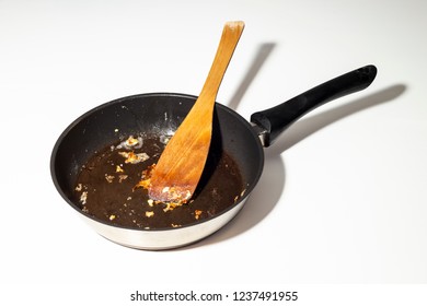 Used dirty iron black frying pan with stick food with wooden spoon in - close up on white background - Powered by Shutterstock