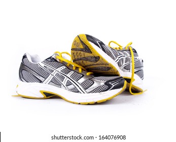 Used Dirty Pair Of Running Shoes Over A White Background